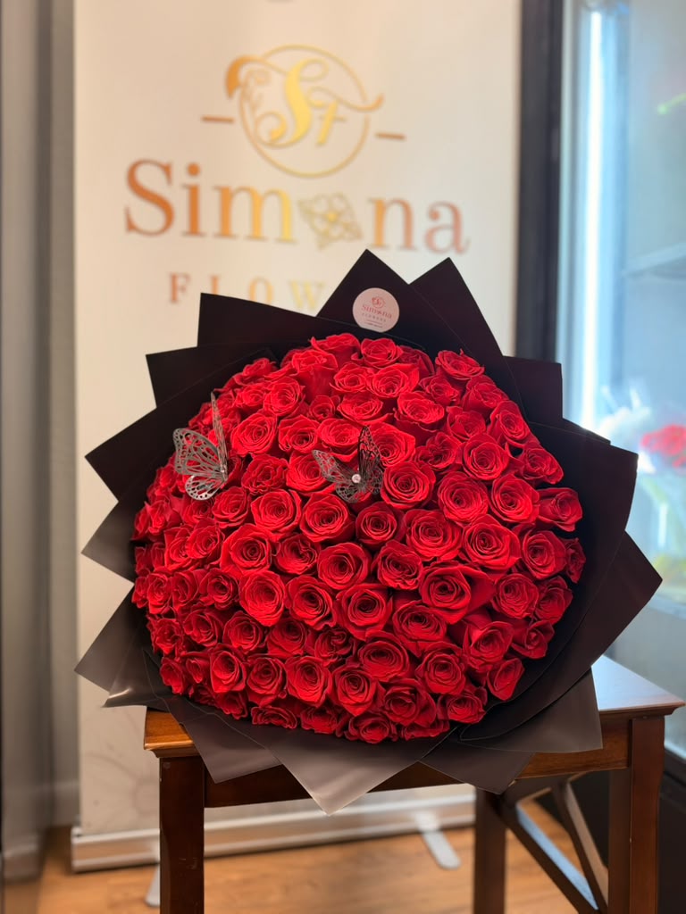 Crimson Reverie red rose bouquet in black wrapping with decorative butterflies