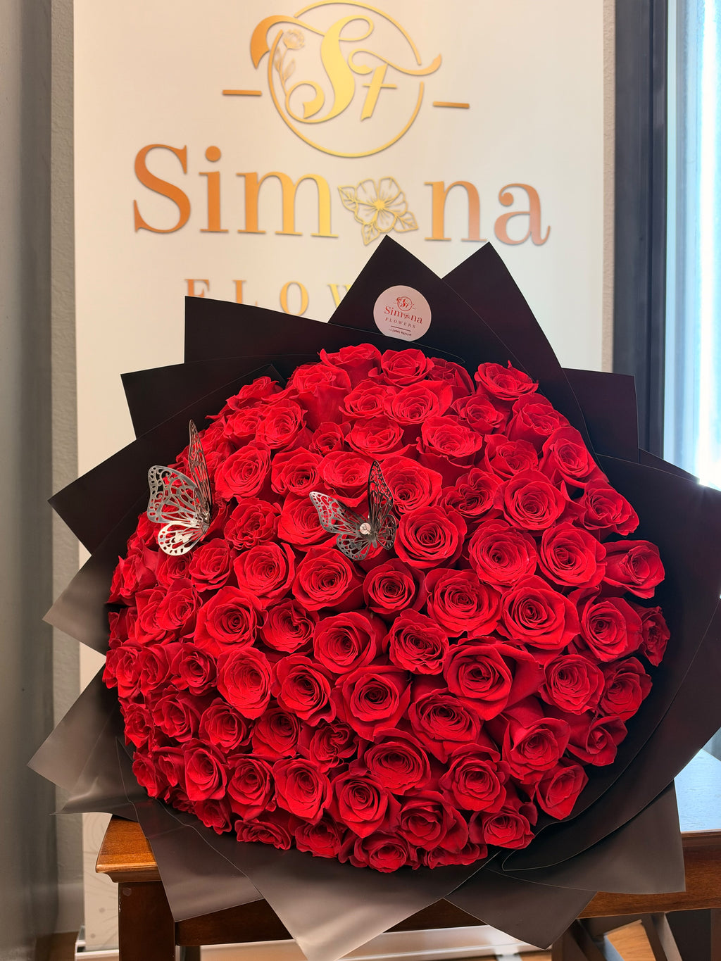 Close-up of Crimson Reverie red roses and decorative butterfly accents