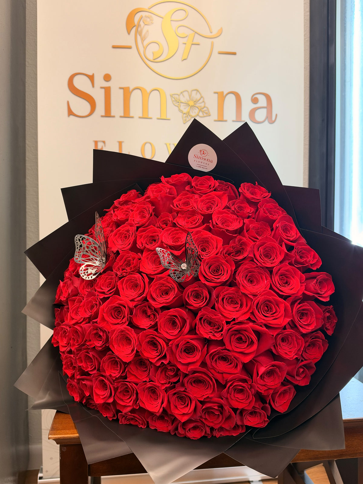 Close-up of Crimson Reverie red roses and decorative butterfly accents