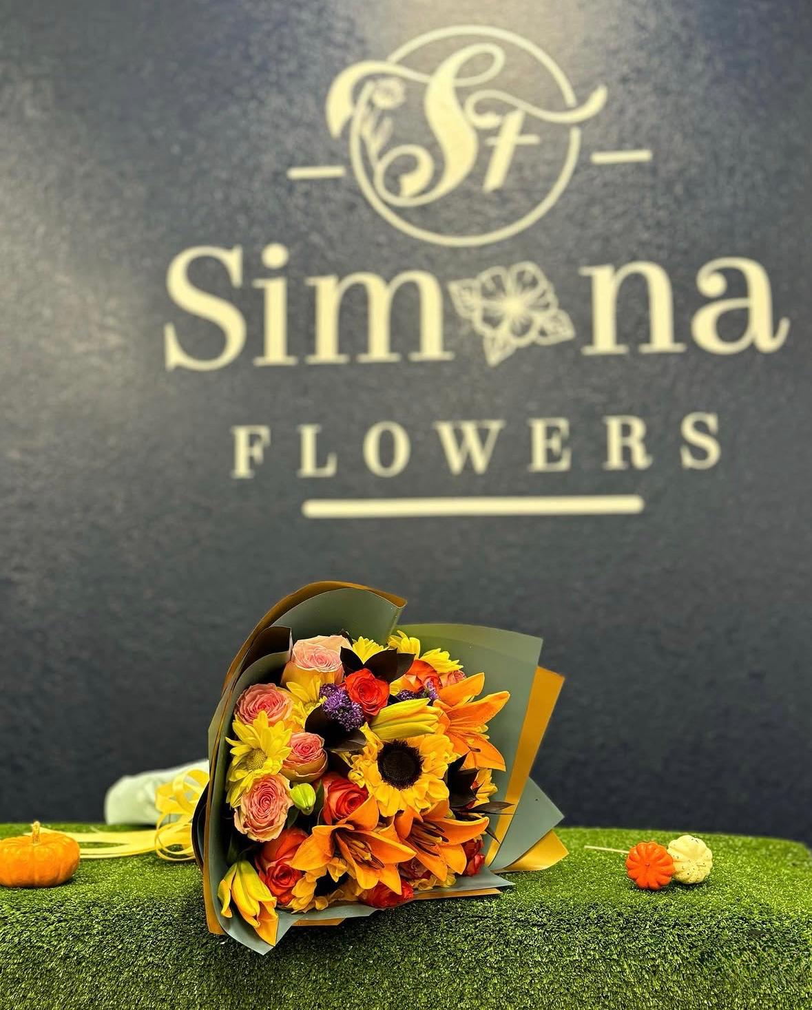 Fall bouquet with sunflowers, orange flowers and pink roses wrapped in layered paper